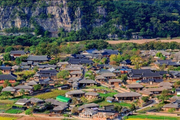 산기슭에 위치한 전통 한옥 마을의 항공사진. 초가지붕과 기와지붕이 어우러져 있고, 주변에는 울창한 숲과 절벽이 보인다.