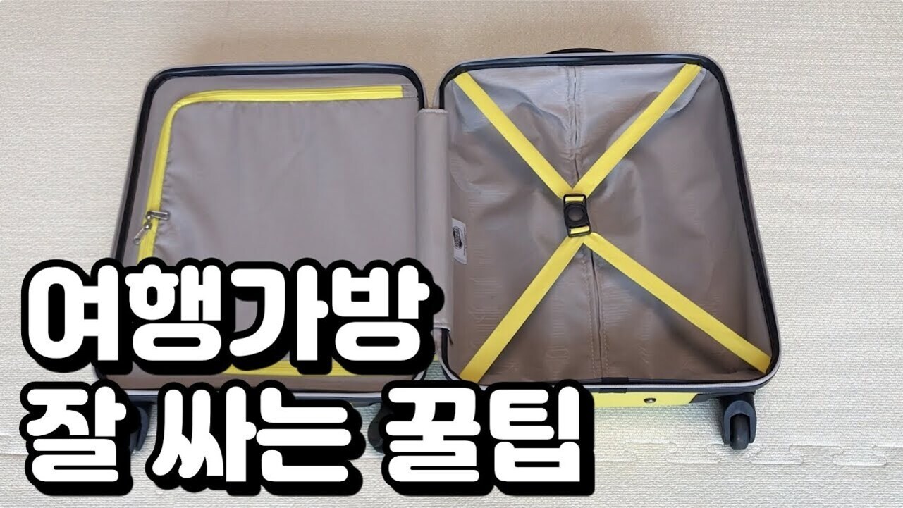 빈 여행가방이 바닥에 펼쳐져 있고, 화면 하단에는 '여행가방 잘 싸는 꿀팁'이라는 한국어 문구가 크게 적혀 있다.