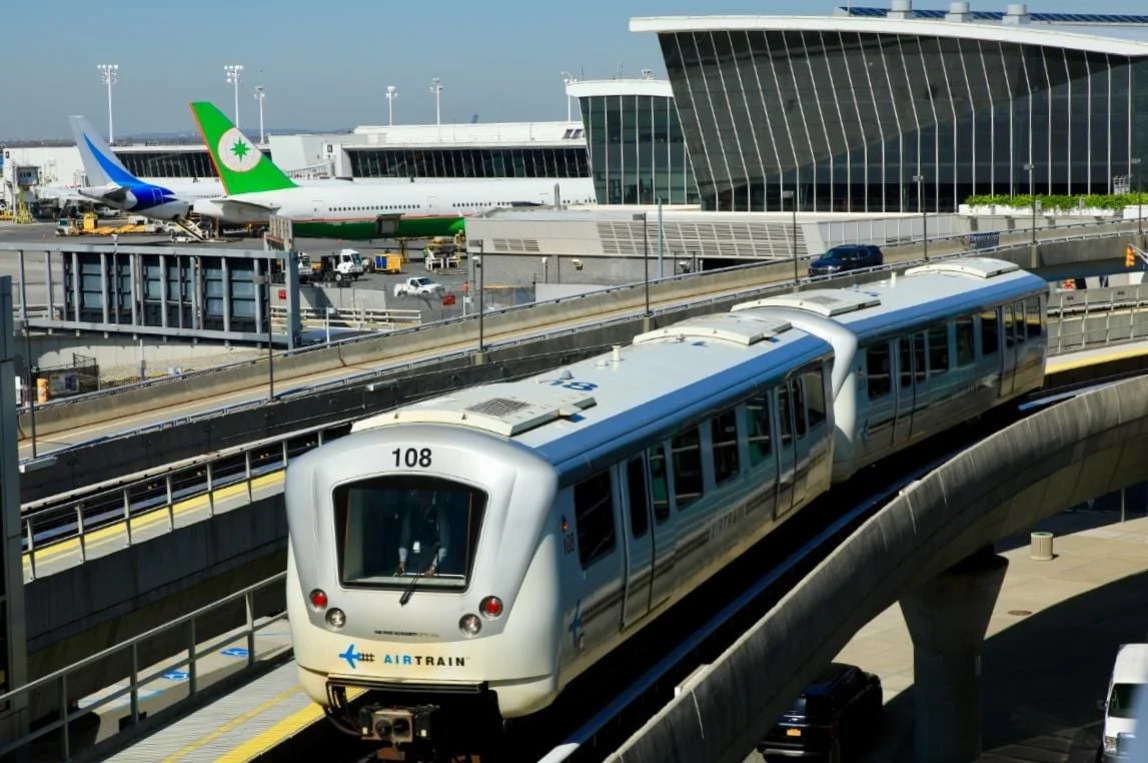 공항 터미널 앞을 달리는 에어트레인과 배경에 주차된 여객기들